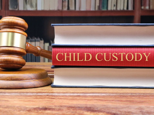 A judge gavel sits on top of a book with the word child custody.
