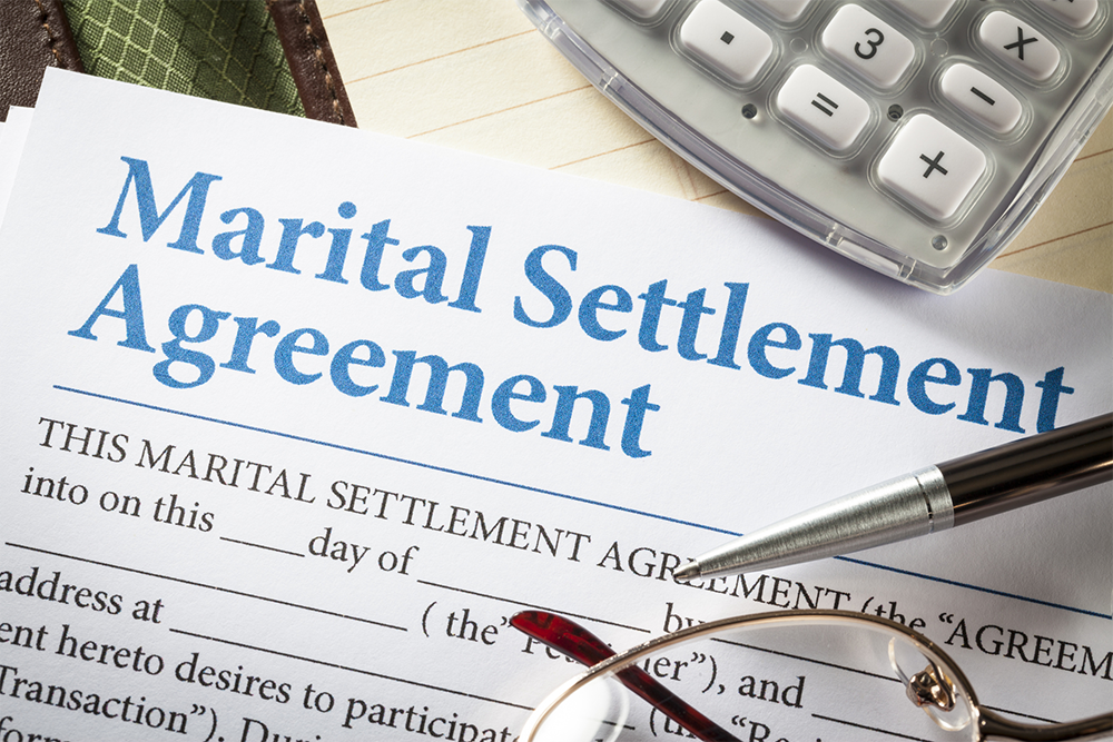 A marital settlement agreement with glasses and a pen.